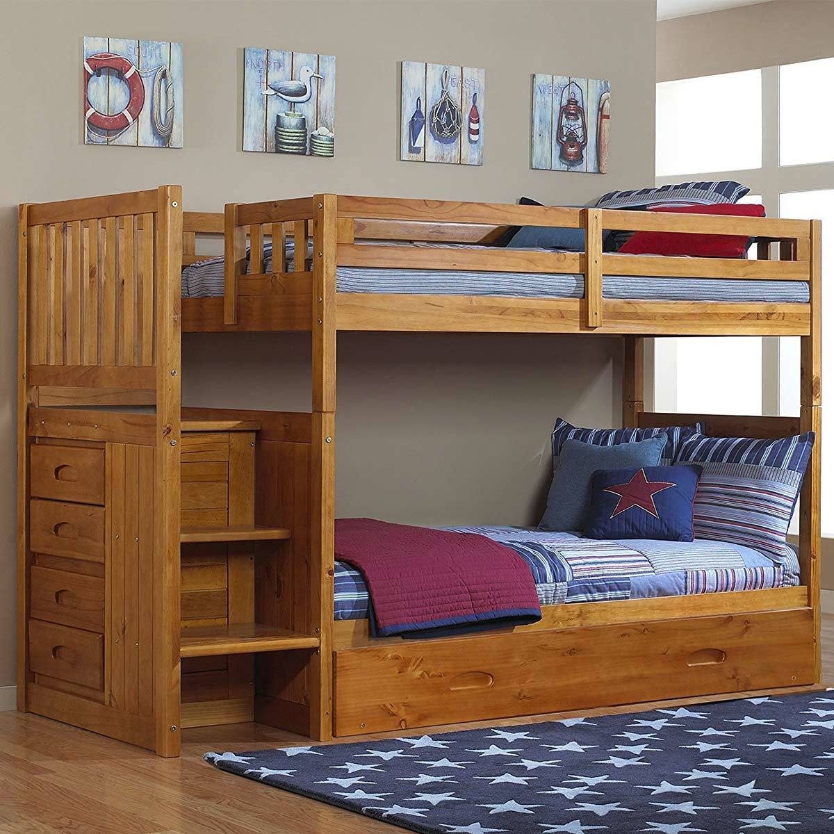 A wooden bunk bed with a storage unit features two beds, striped bedding, and pillows. The room has wall art and a rug with stars.
