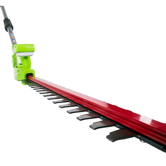A green electric hedge trimmer extends forward, featuring a long red cutting blade with teeth, designed for trimming plants in outdoor environments.
