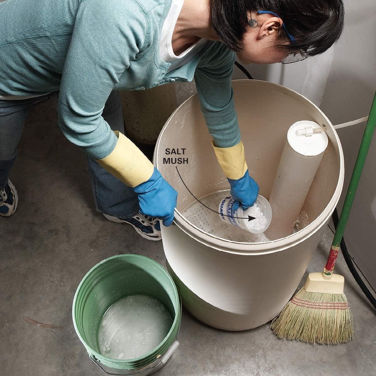 A person wearing blue gloves pours a substance labeled "SALT MUSH" into a large container, while a green bucket and broom are nearby.