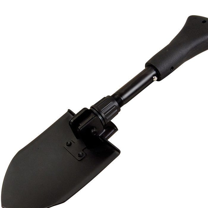 A compact black shovel with a detachable blade is positioned diagonally, suitable for digging in various outdoor environments, including gardens or construction sites.