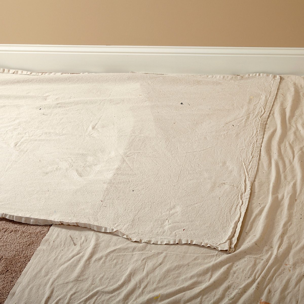 Laying down narrow drop cloths next the walls | Construction Pro Tips