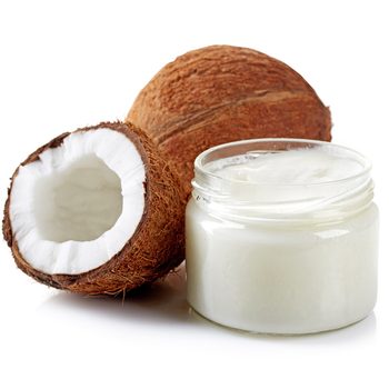 A halved coconut and a jar of coconut cream sit side by side against a white background, emphasizing their natural ingredients and tropical origin.