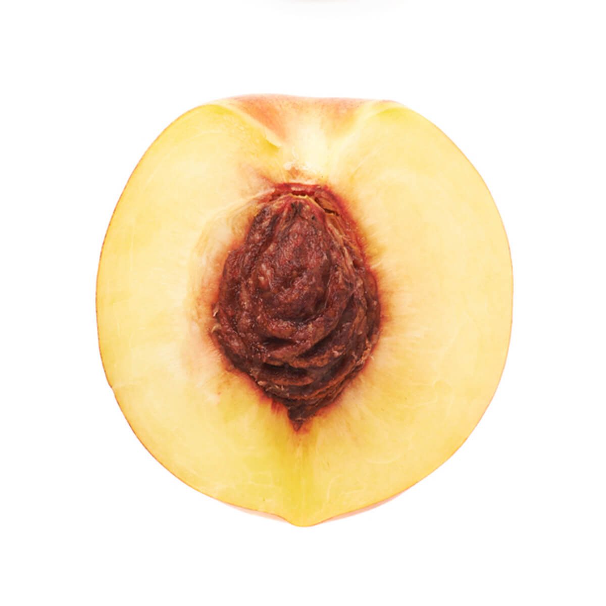 A halved peach displays its smooth, yellow interior and brown pit, set against a plain white background.