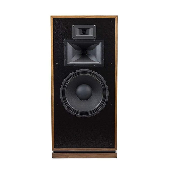 A large speaker stands upright, featuring three speaker components: a horn tweeter, mid-range, and a wide bass driver, all within a wooden frame.