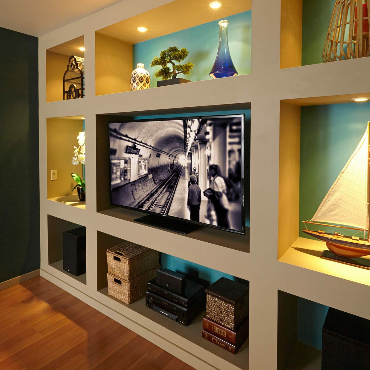 A television displays a black-and-white subway scene, surrounded by decorative shelves with plants, vases, and a model sailboat in a cozy living room.