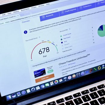 A laptop screen displays a credit report, showing a score of 678 labeled as "Fair," with options for credit cards and a promotional offer for a card.