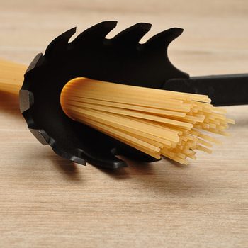 A black pasta scoop is holding uncooked spaghetti against a wooden surface, ready for cooking. The scoop's design features pointed edges for effective pasta handling.