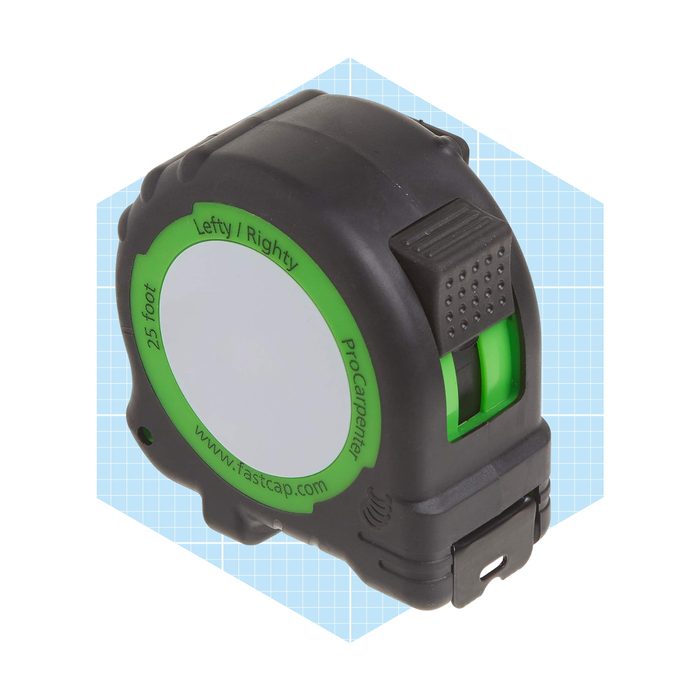 A black and green tape measure sits on a light blue grid background, showcasing its retractable measuring feature, typically used in carpentry or construction tasks.