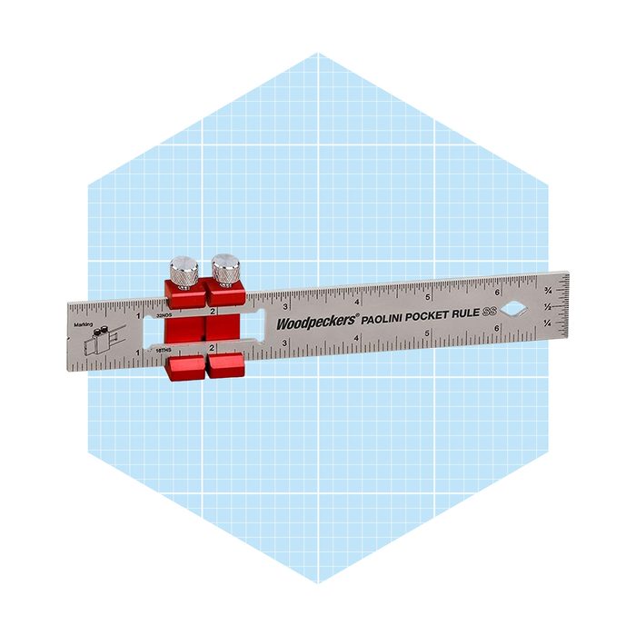 A stainless steel ruler with red clamping pieces rests horizontally on a light blue grid background, designed for precise measurements in woodworking.