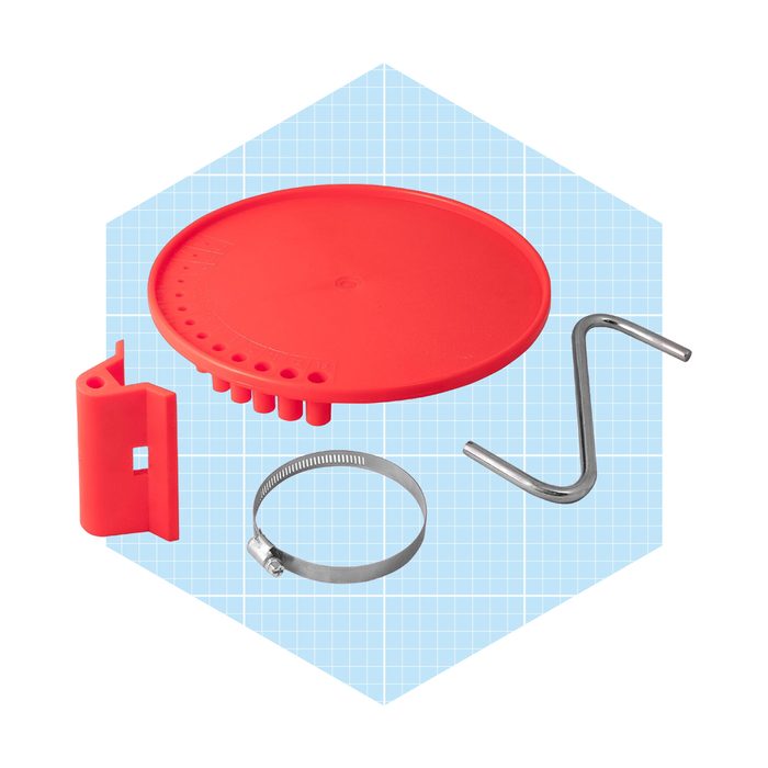 A red circular platform with multiple tools—including a clamp, a hook, and a red plastic piece—laid out against a light blue grid background.