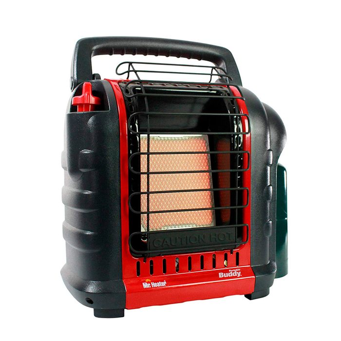 A portable gas heater emits heat, enclosed in a black and red metal casing with a protective grill, suitable for outdoor or indoor use.