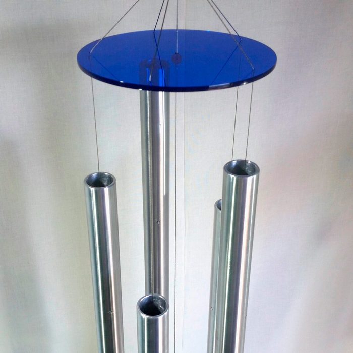 A set of silver metal tubes hangs from a circular blue top, swaying gently in the air against a light-colored background.