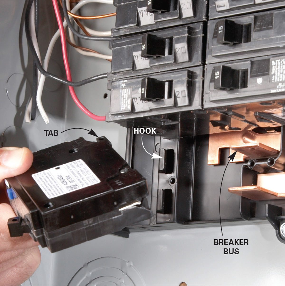 A person inserts a circuit breaker into a panel, aligning a tab and hook with the breaker bus, surrounded by wires and other breakers.