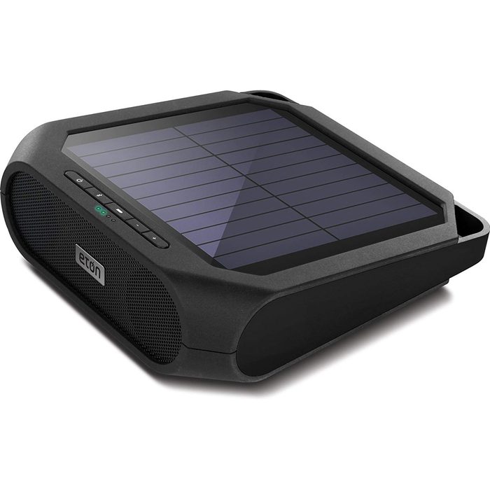 A portable speaker with a solar panel on top plays music outdoors, featuring control buttons and a durable design, ideal for outdoor activities.