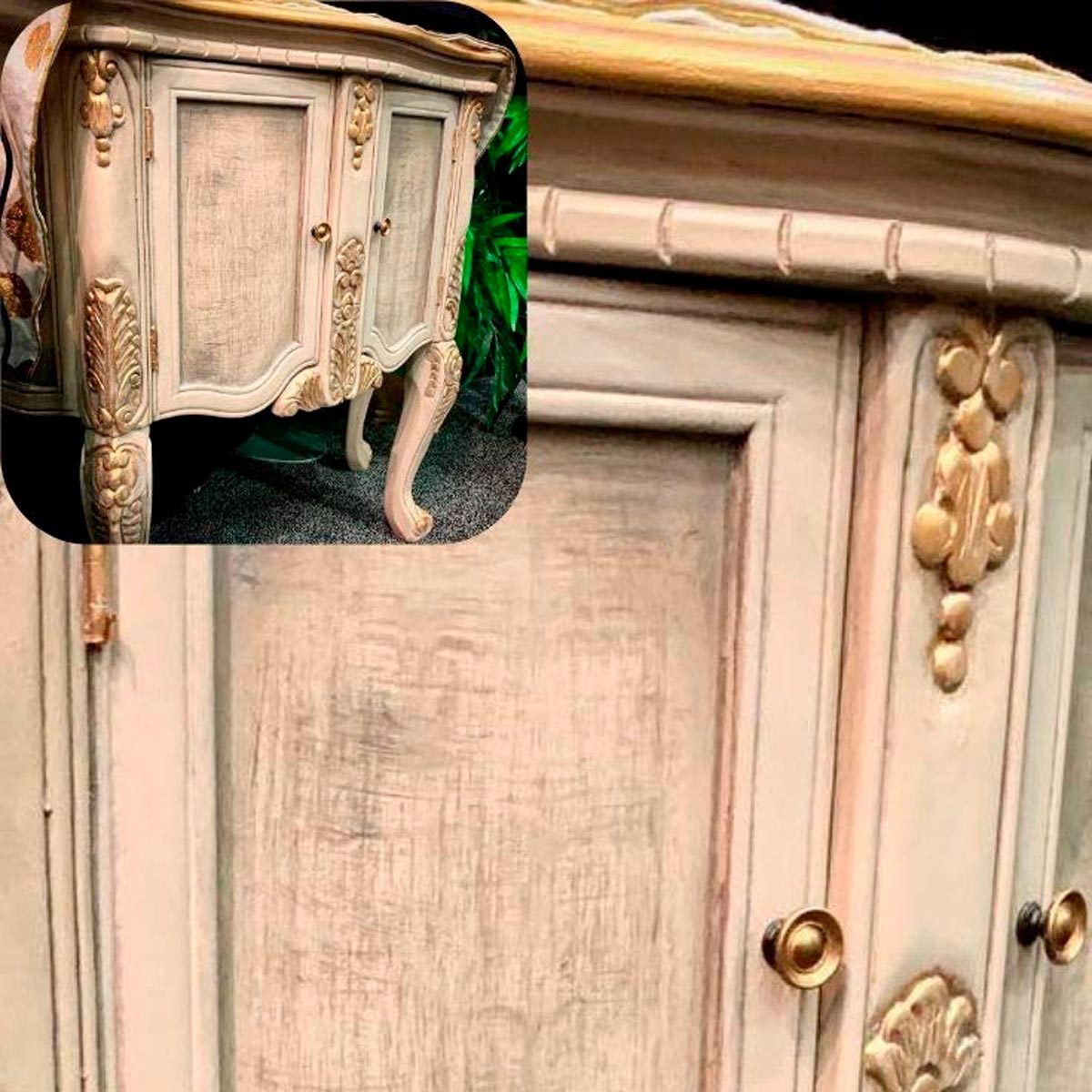 A decorative cabinet features ornate carvings and golden accents, standing on curvy legs against a textured surface, with greenery in the background.