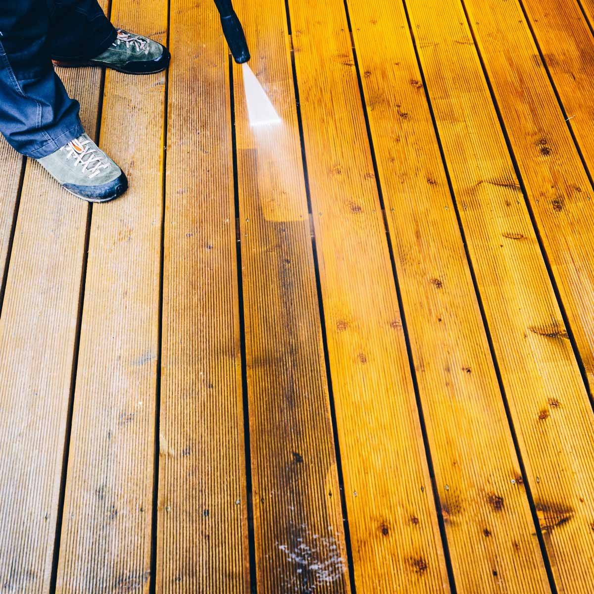 Man-pressure-washes-a-deck