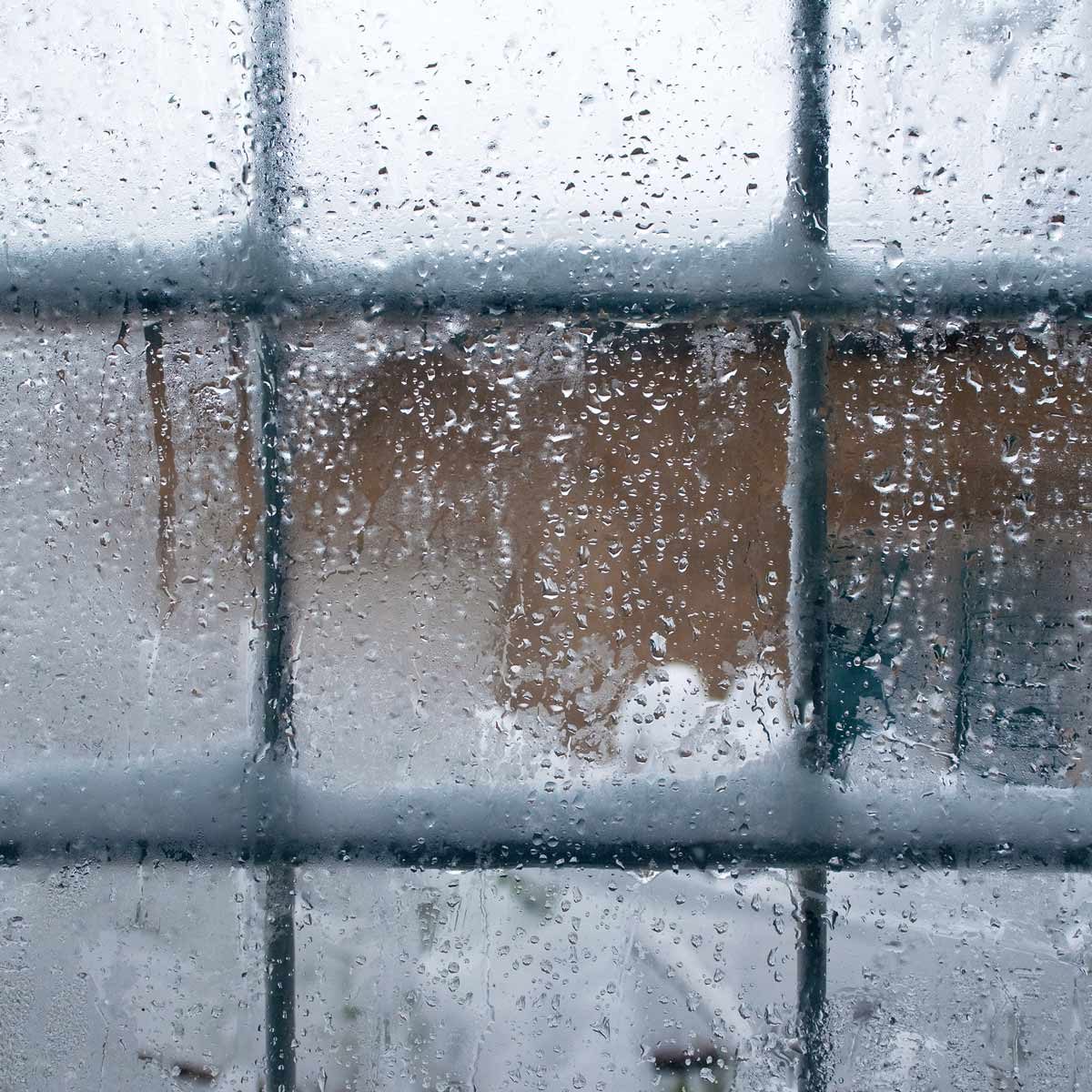 Winter window, drops of water and snowflakes on a window panel