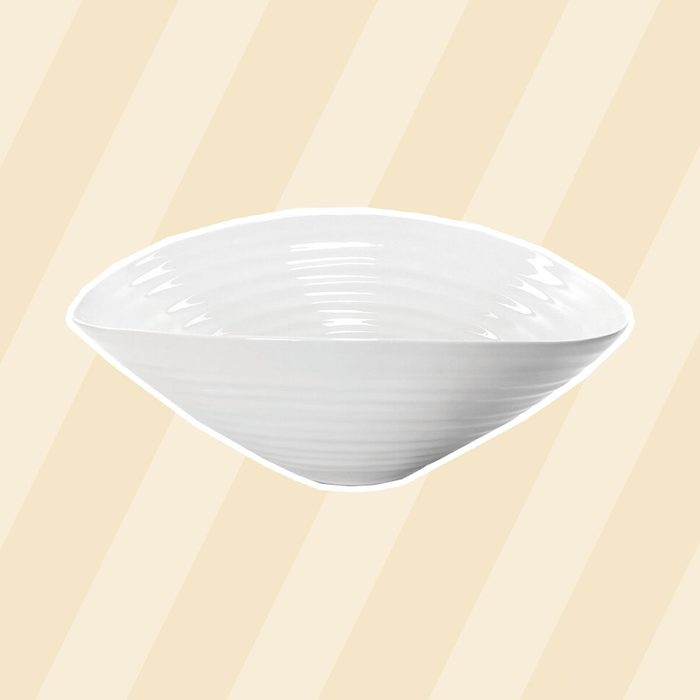 A white, curved bowl sits centered against a light yellow striped background, conveying a clean and modern aesthetic.