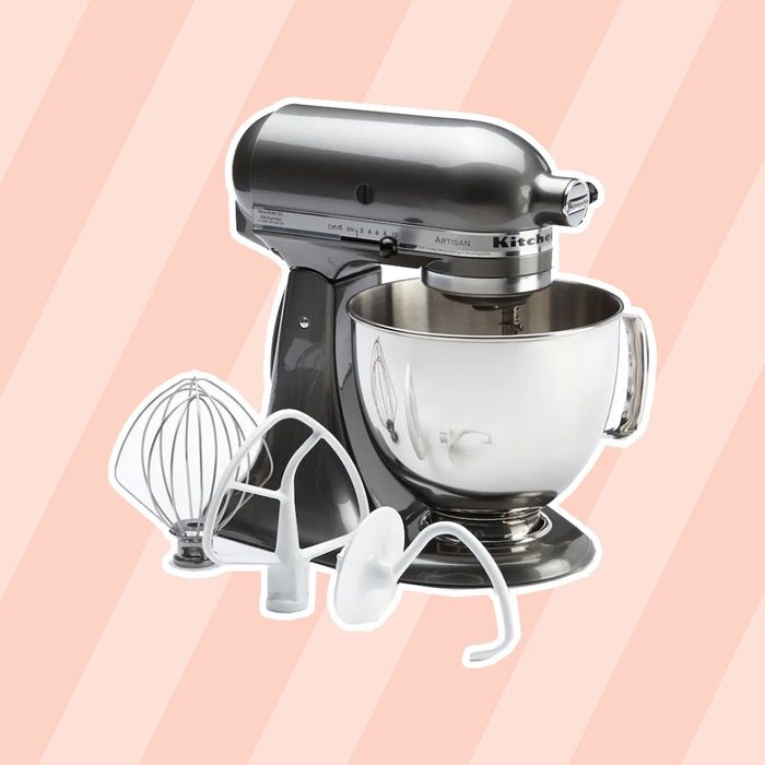 A metallic stand mixer sits on a light striped background, accompanied by various mixing attachments, ready for baking or food preparation tasks.