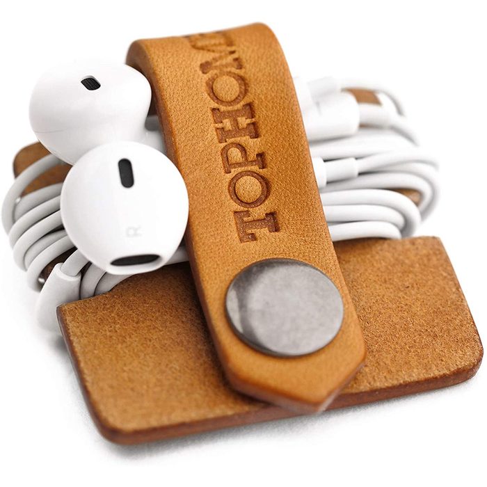 White earbuds are neatly wrapped and secured with a brown leather strap embossed with 