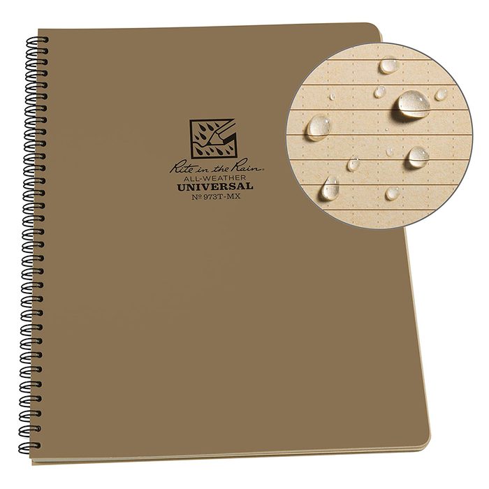 A brown spiral-bound notebook rests flat, featuring an all-weather design. Water droplets appear on a close-up of its lined pages, indicating moisture resistance.