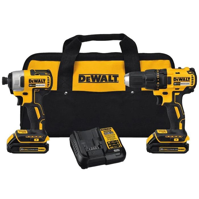 Two cordless power tools, a drill and impact driver, sit alongside a battery and charger, all arranged on a black and yellow carrying case.