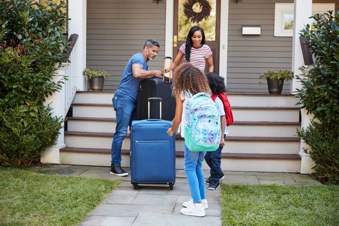 Family With Luggage Leaving House For Vacation