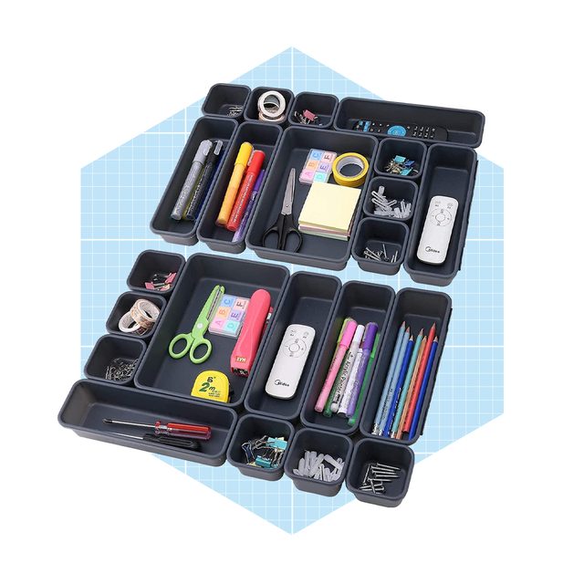 Organizational trays hold various office supplies like scissors, markers, and sticky notes, arranged on a blue grid background for clarity and accessibility.