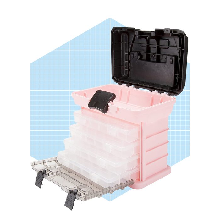 A pink storage box with a black lid is open, revealing several clear, stacked containers inside, set against a light blue grid background.