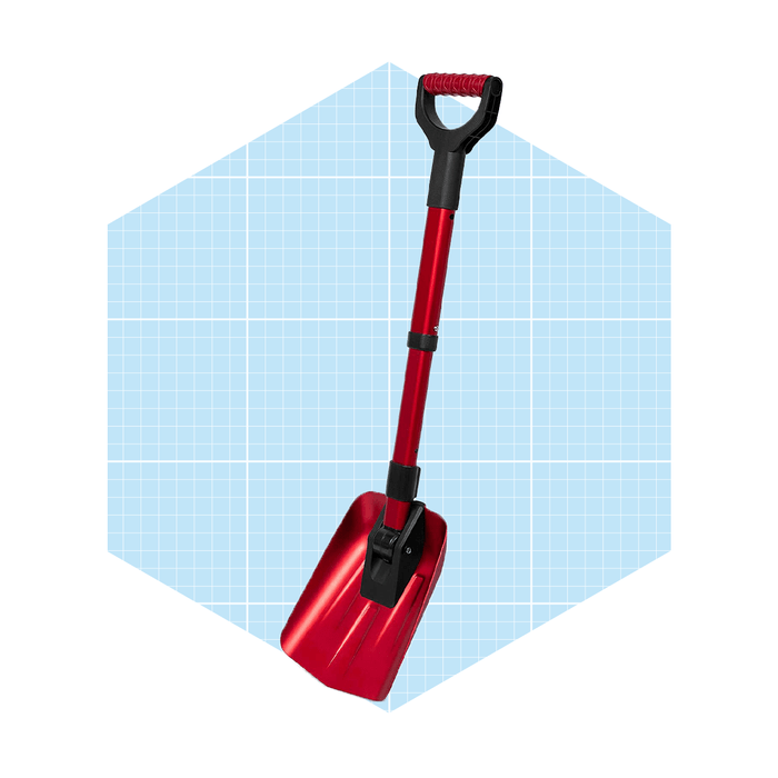 A red shovel stands upright against a light blue grid background, showcasing its shiny metal scoop and sturdy handle.