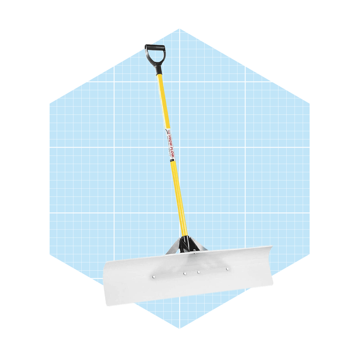 A snow shovel stands upright, featuring a wide blade for snow removal, set against a light blue grid-patterned background.