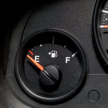 A fuel gauge shows the needle pointing near the "E," indicating a low fuel level in a vehicle's dashboard.