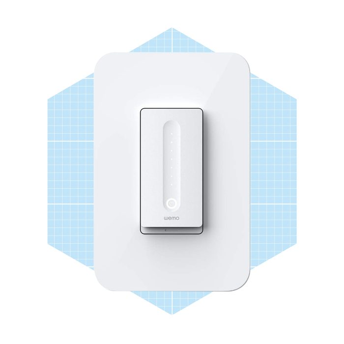 A white smart switch is mounted on a light background, featuring indicator lights and a power button, set against a grid-patterned blue backdrop.