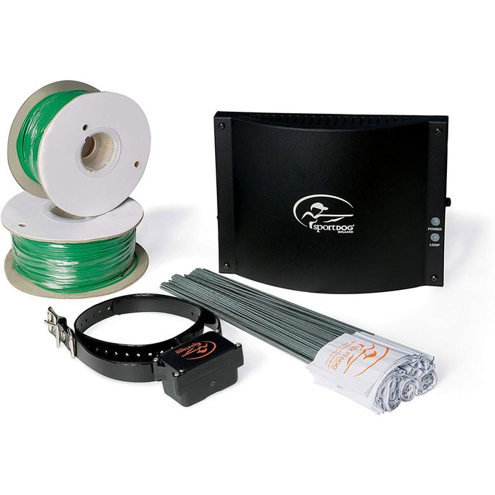 A black electronic device connects with a collar, wire spools, and stakes for creating a pet containment system in an indoor setting.