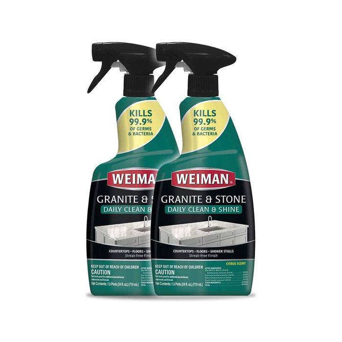 Two spray bottles of Weiman Granite & Stone cleaner are positioned side by side. They are designed for cleaning surfaces like countertops and floors.