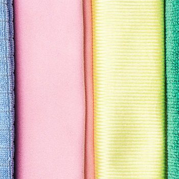 Four pieces of cloth in varying colors—blue, pink, yellow, and green—are arranged side by side, showcasing their textures and hues.