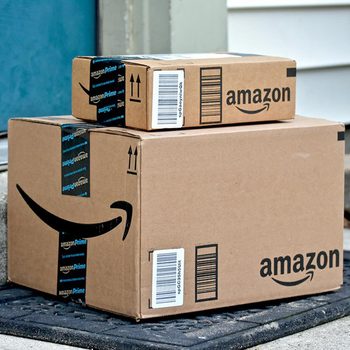 Two Amazon boxes are stacked on a doorstep, indicating a recent delivery outside a residential entrance.