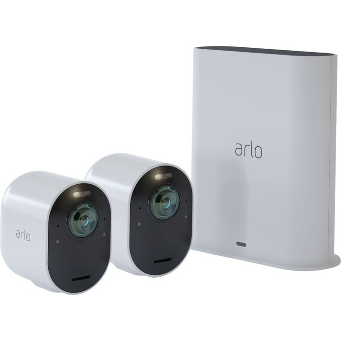 Two round, white security cameras are positioned next to a rectangular base station, all featuring the 