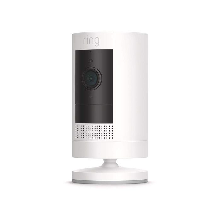 A white security camera stands on a round base, actively monitoring its surroundings with a black lens and features for capturing video content.