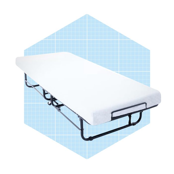 A white folding bed rests on a black metal frame against a light blue grid background, suggesting a portable sleeping solution.