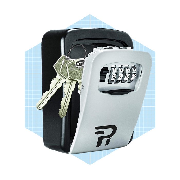 A combination lockbox is mounted on a surface, holding keys. It displays a four-digit code mechanism against a light blue geometric background.