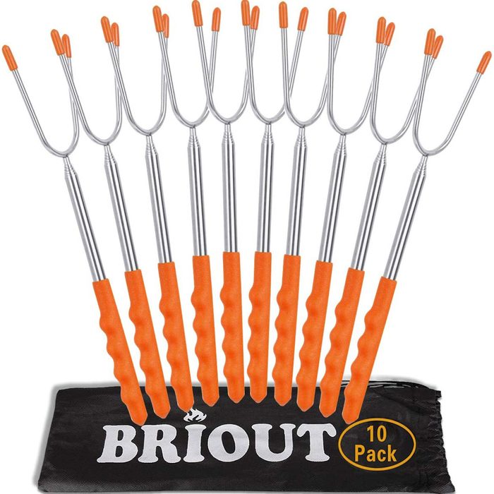 A set of ten stainless steel roasting forks with orange rubber grips rests on a black bag labeled 