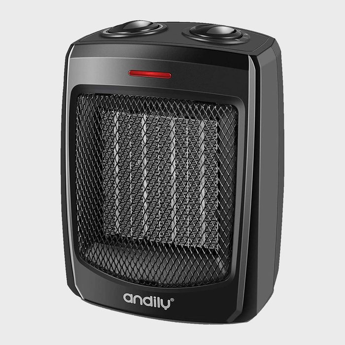 A small black space heater is emitting heat, featuring a mesh front and two control knobs on top, set against a plain background.