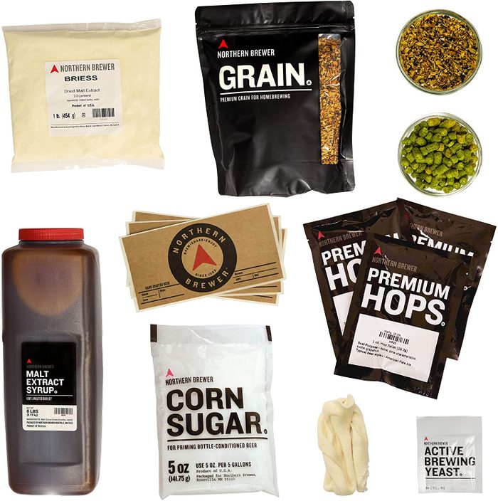 Ingredients for homebrewing are displayed, including malt extract, grain, hops, corn sugar, yeast, and brewing equipment, laid out on a white background.