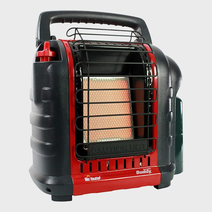 A portable heater with a metal grid is generating warmth, designed for indoor use, featuring a handle for easy transportation and labeled with a caution sign.