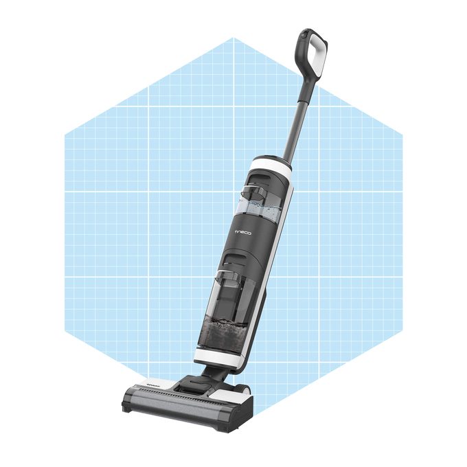 A vertical vacuum cleaner stands upright, showcasing transparent compartments for dirt and water, against a light blue grid background.