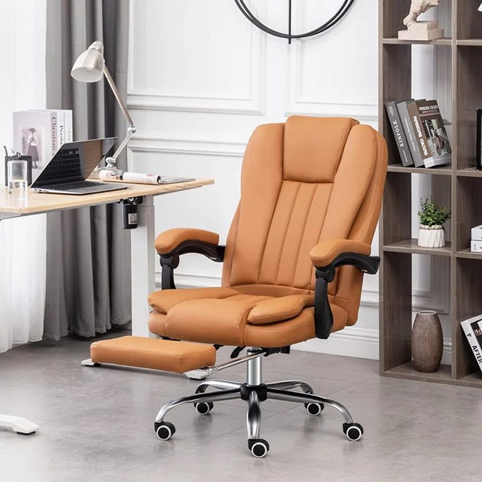A tan executive chair with a reclining feature occupies a modern office space, next to a desk with a laptop and bookshelves filled with items.