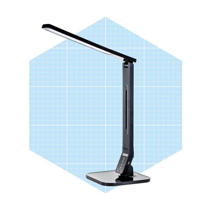 A modern desk lamp stands upright, illuminating a workspace, against a light blue grid background, showcasing its sleek design and adjustable height features.