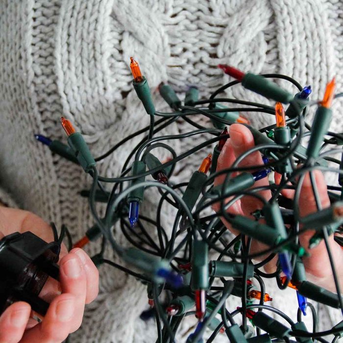hands holding broken Christmas lights