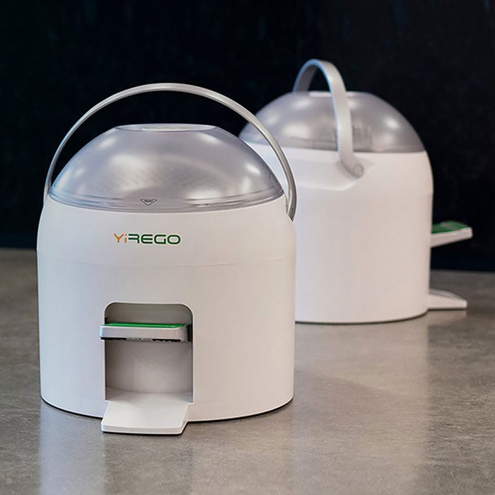 Two white, dome-shaped devices with transparent tops sit on a gray surface, suggesting a modern cleaning or sterilization function in a stylish environment.